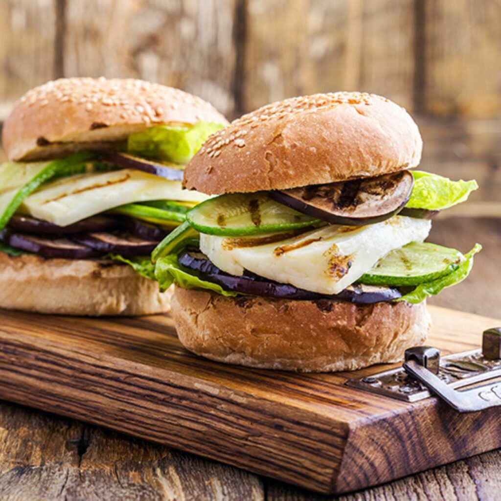Halloumi Burger werden auf einem Holzbrett serviert.