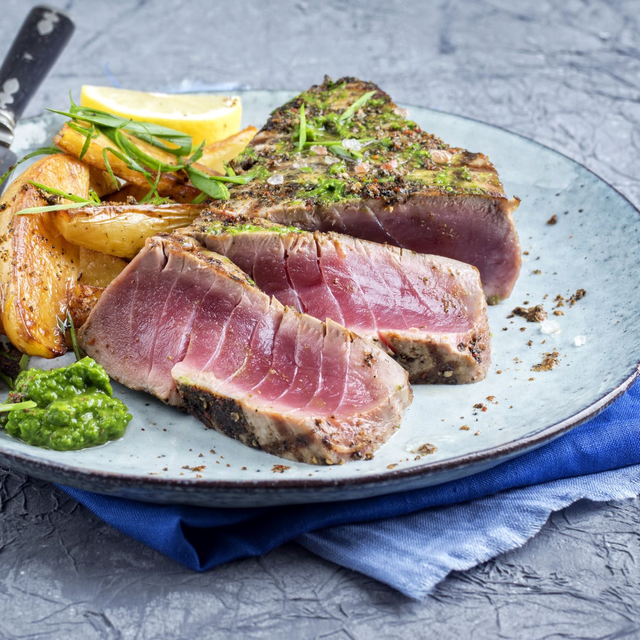 Thunfisch-Steak mit Basilikum-Pesto wird zusammen mit Kartoffeln serviert.