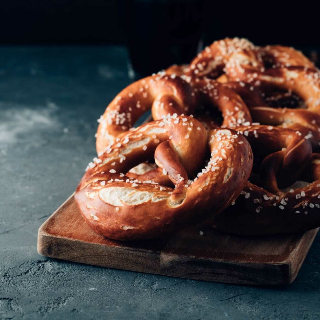 Laugenbrezeln werden auf einem Holzbrett gestapelt serviert.