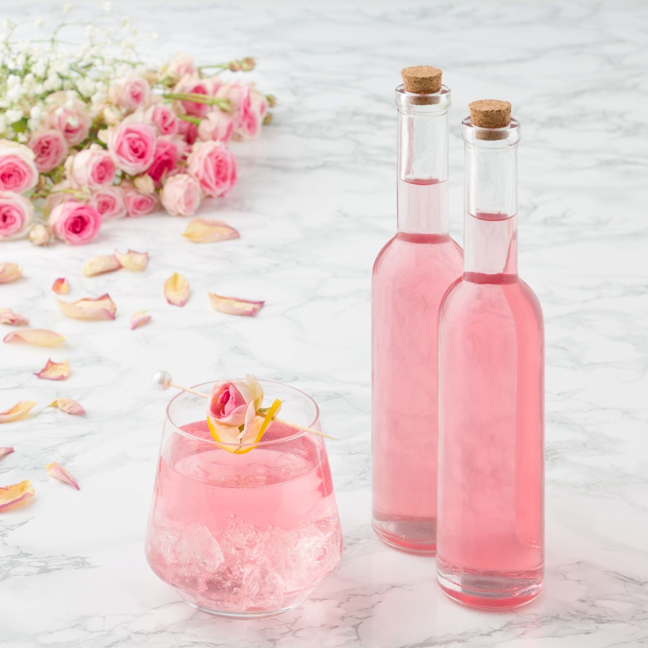A rózsaszirupot két kis üvegben és egy pohárban jégkockákkal tálalják.