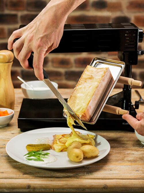Walliser Raclette: Käse wird vom Grill auf Kartoffel geschabt.