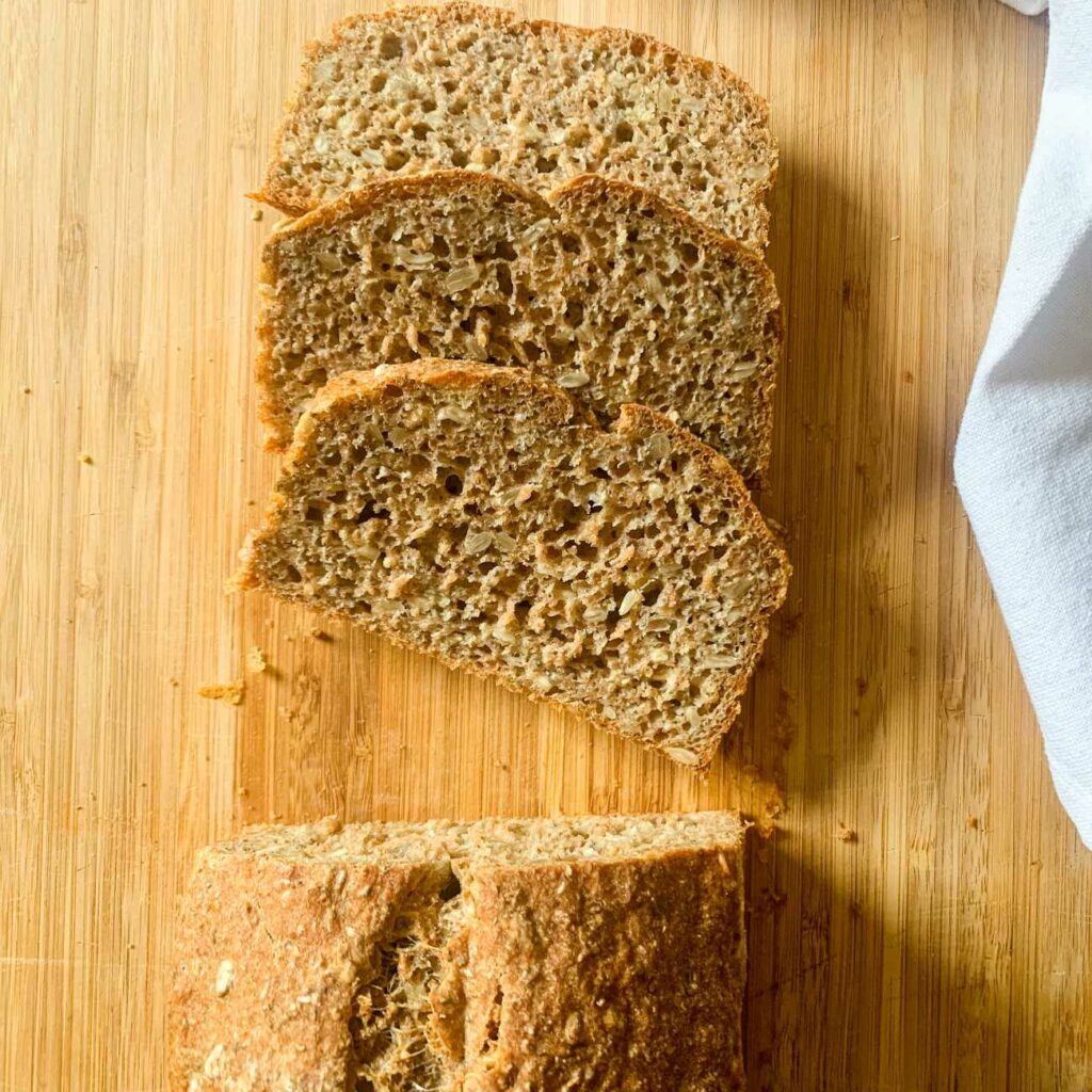 Chiabrot mit Sonnenblumenkernen wir angeschnitten auf einem Holzbrett gezeigt.