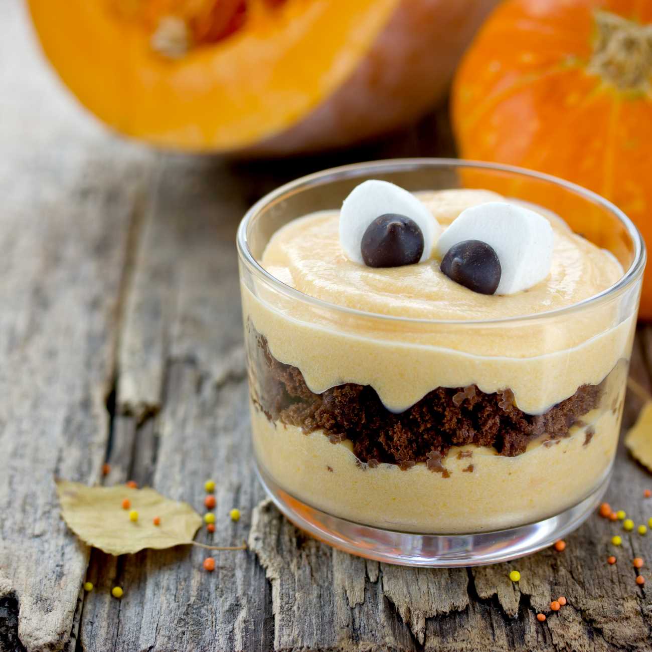 Halloween Dessert im Glas mit Marshmallow-Augen wird auf einem Holz-Untergrund gezeigt.