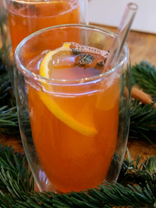 Hot Aperol wird in einem doppelwandigen Glas mit Orange und Thymian gezeigt. 