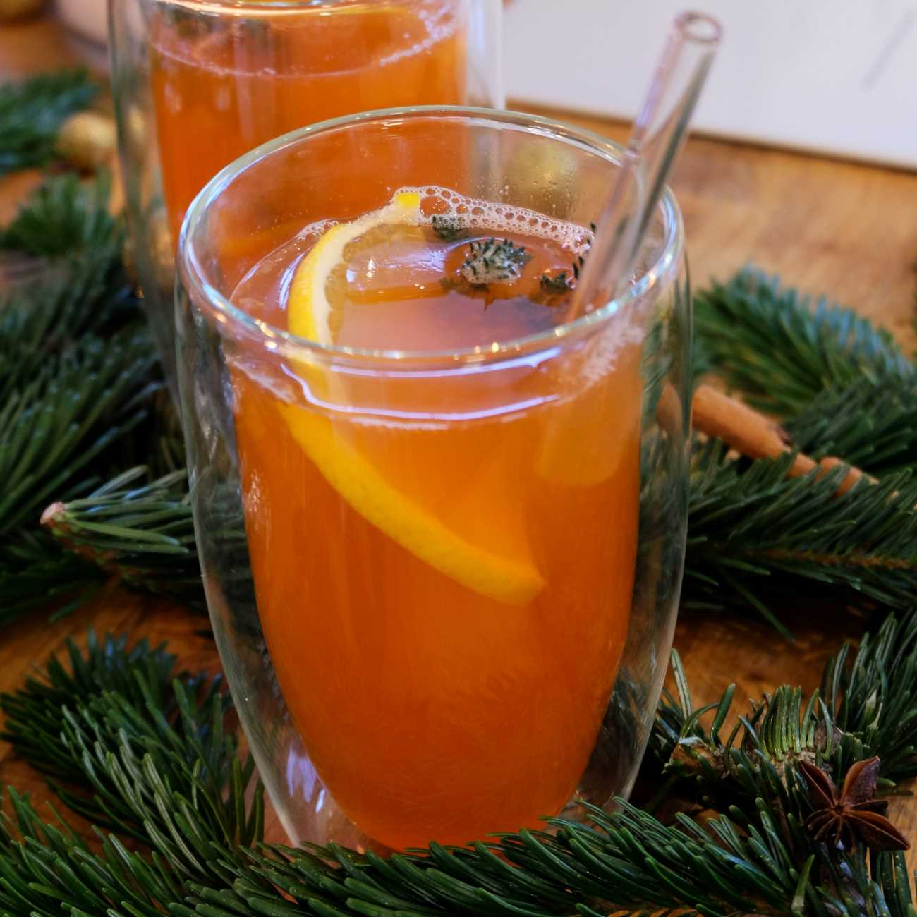 Hot Aperol wird in einem doppelwandigen Glas mit Orange und Thymian gezeigt.