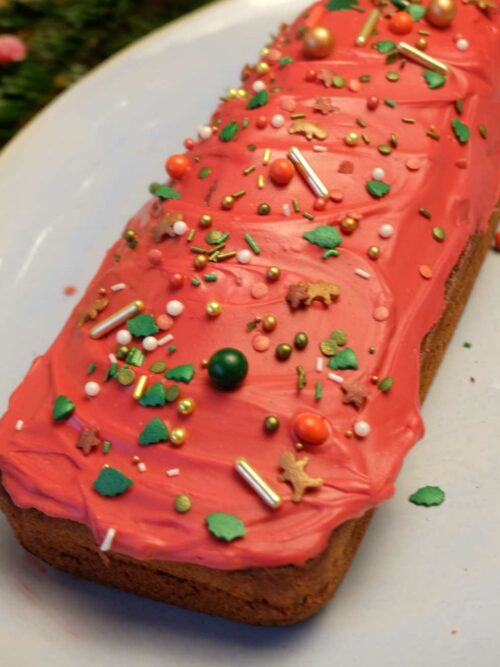 Red Velvet Cake mit weihnachtlicher Verzierung wird auf einer Servierplatte mit Streuseln präsentiert.