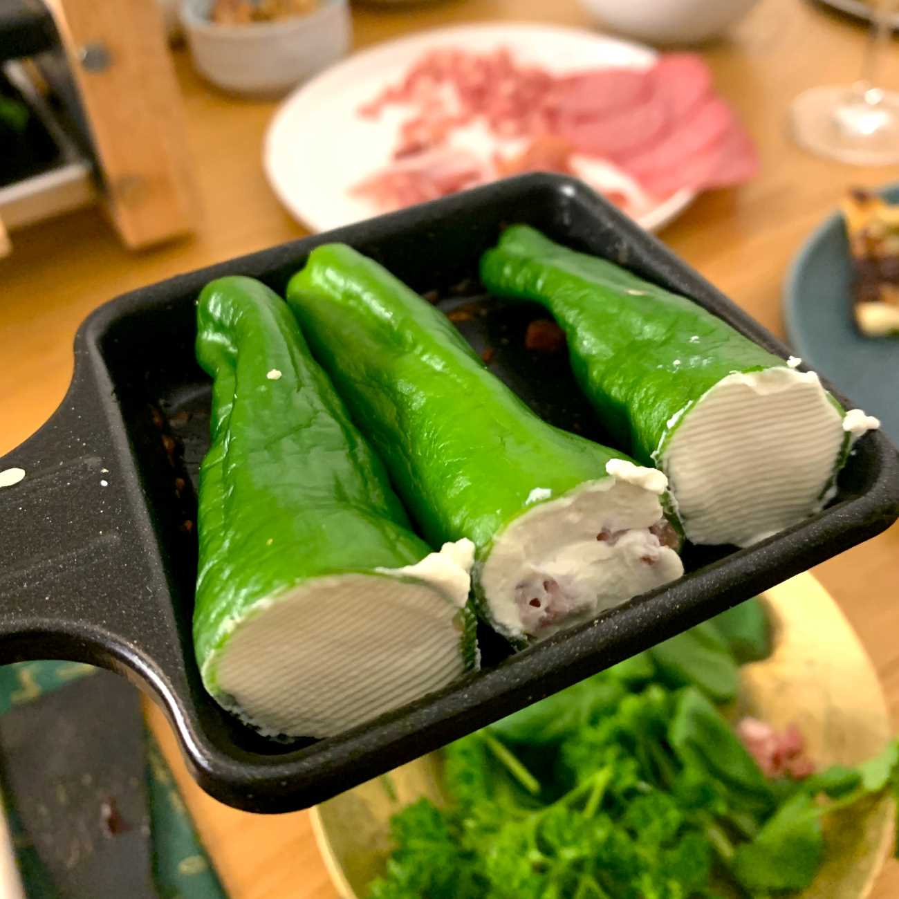 Gefüllte Pimentos werden zu dritt in einem Raclette-Pfännchen gezeigt.