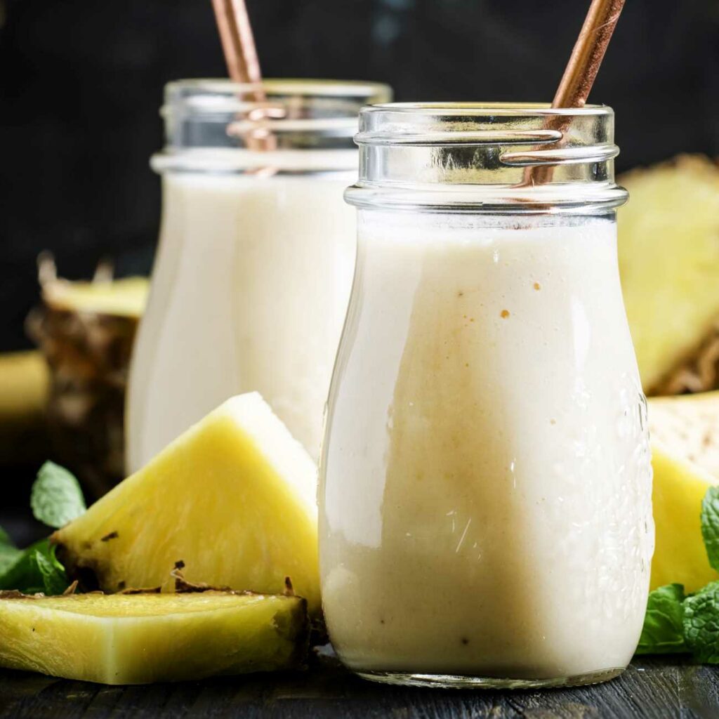 Ananas Smoothie wird in einem Schraubglas mit Strohhalm gezeigt.