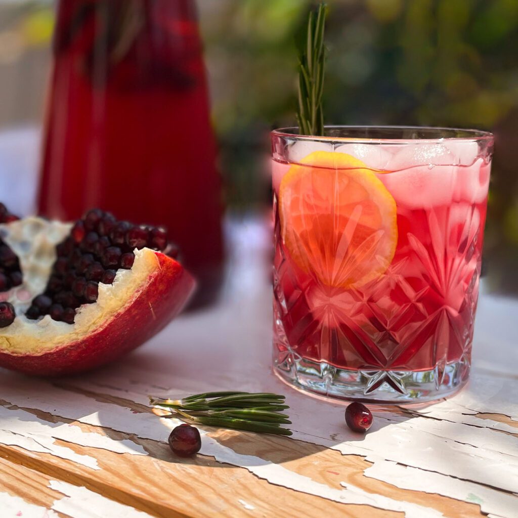 Granatapfel Limonade wird in einem Glas mit Zitronenscheibe gezeigt.